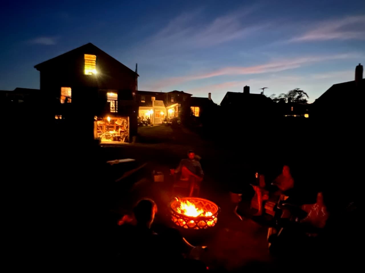 The Long family seated together around a campfire at dusk, Westport Point, Massachusetts