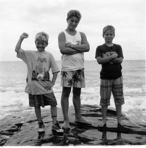 Three boys on the rocks — black and white